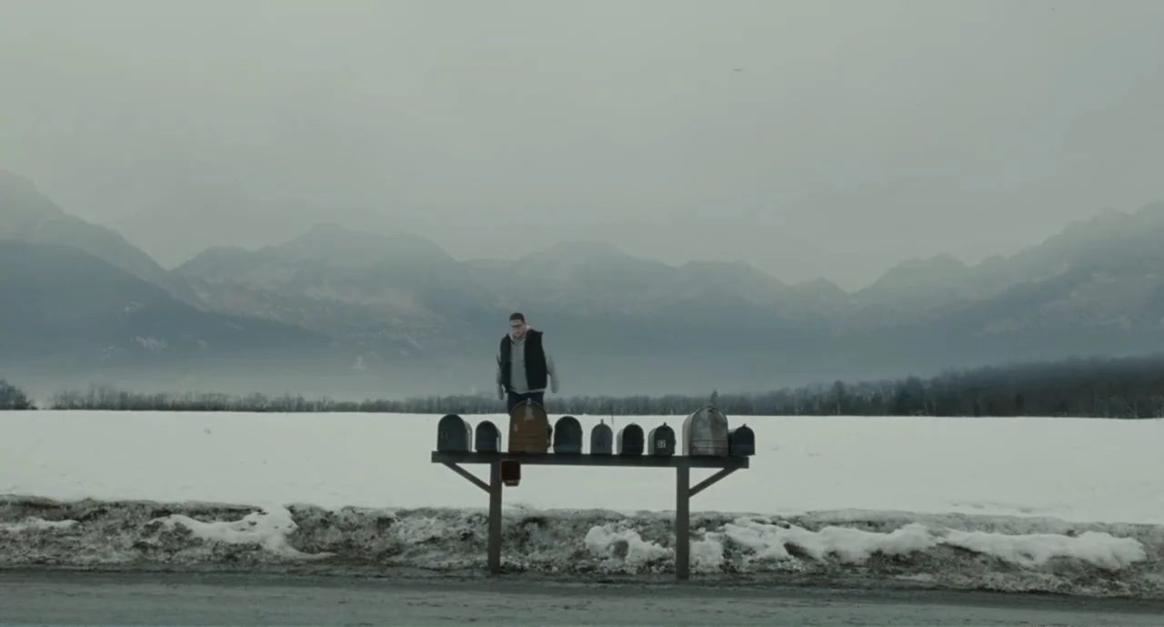 Bad Boys: A True Story (2003) movie still: wide — An open snowy field sits before a backdrop of hazy, cloud-covered mountains. A young man wearing a…
