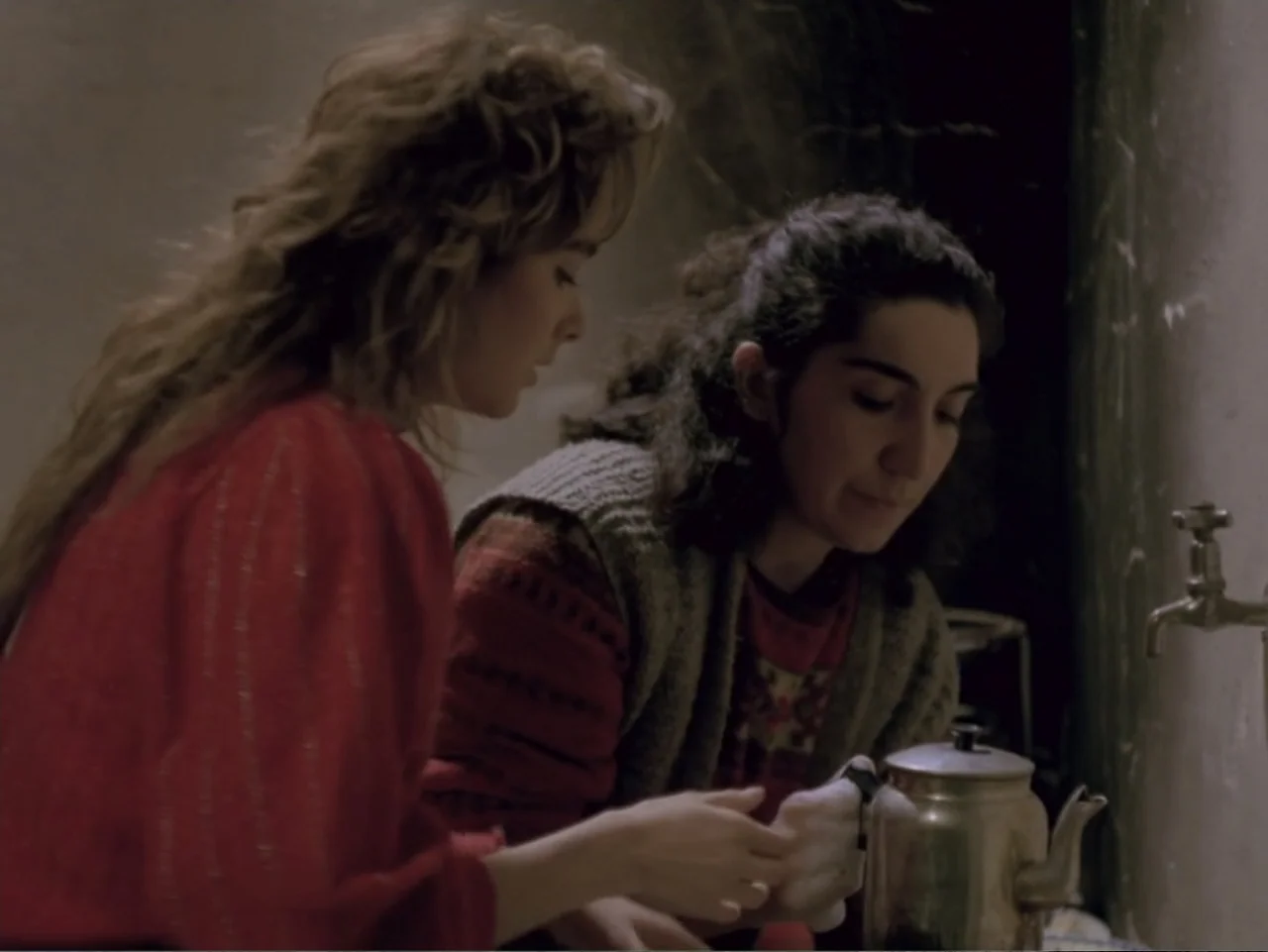 Don't Let Them Shoot the Kite (1989) movie still: medium — An interior kitchen space with a faucet and a metal surface near a wall. Two women are…