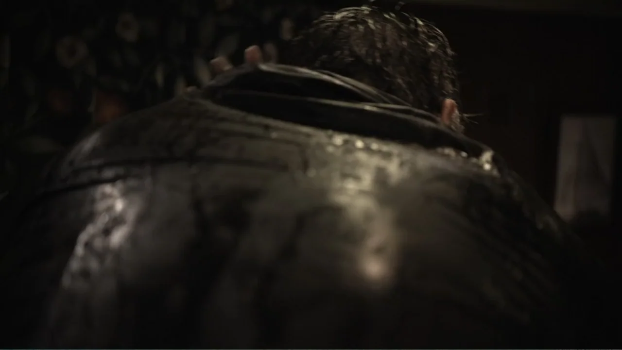 Capsized: Blood in the Water (2019) movie still: closeup — A dark indoor space is occupied by an individual viewed from behind. The person has wet…