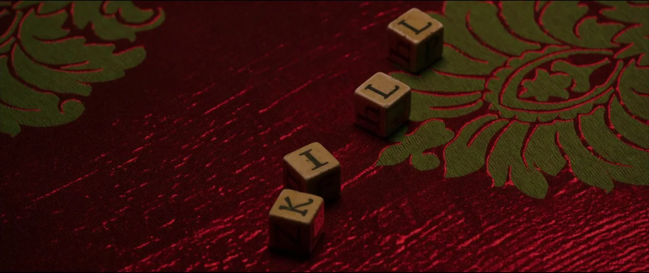 Insidious: Chapter 2 (2013) movie still: closeup — A deep red fabric with a raised olive green damask pattern covers a surface. Four small wooden…