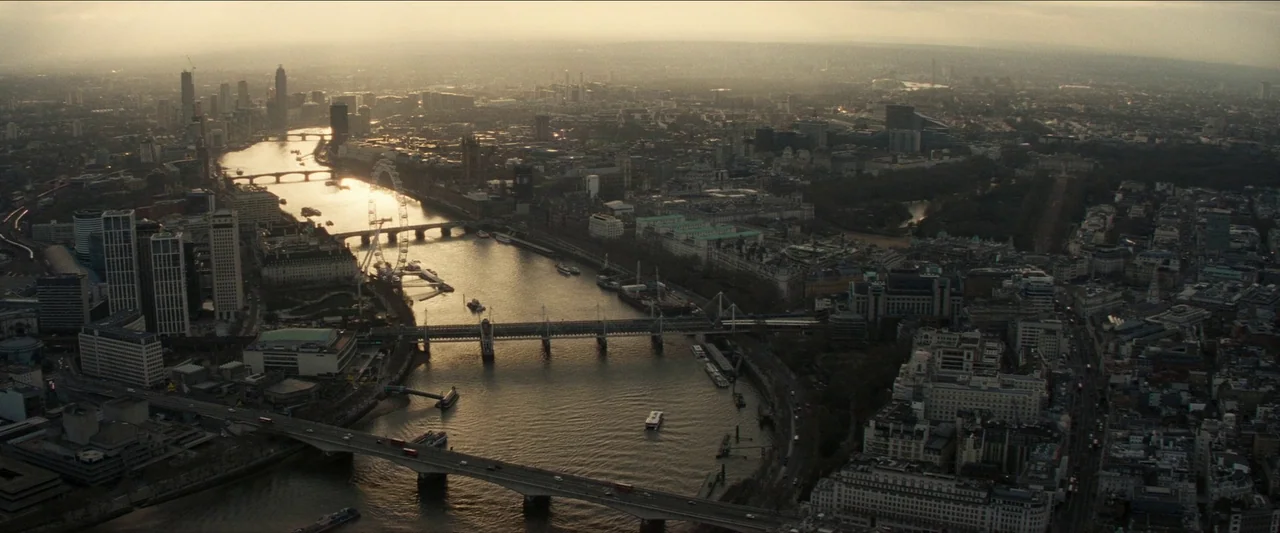 No Time To Die (2021) movie still: establishing — A high-altitude aerial view of London showcases the River Thames winding through dense urban…