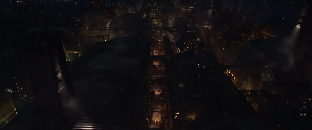 Solo: A Star Wars Story (2018) movie still: establishing — A vast, dark industrial complex stretches across the frame at night with smoking vents.…