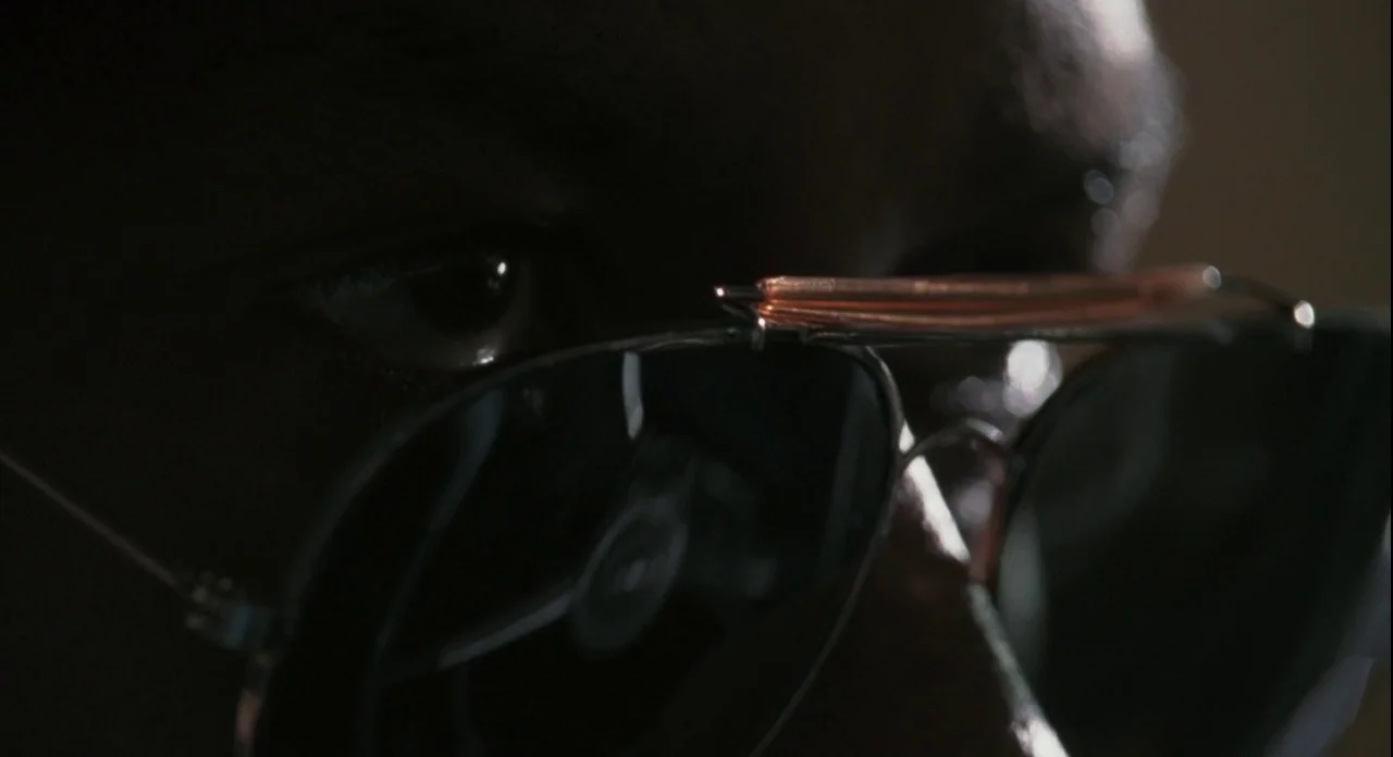 American Gangster (2007) movie still: closeup — A dark indoor space where the focus is restricted to a close-up of a human eye. The subject wears…
