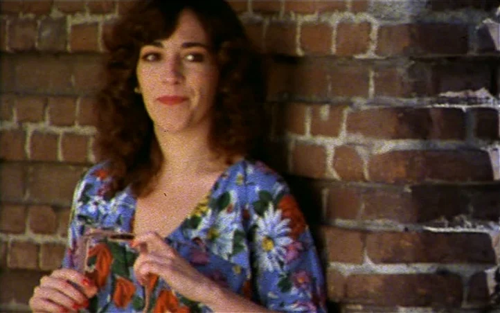 Pepi, Luci, Bom and Other Girls Like Mom (1980) movie still: medium — A woman stands in front of a rustic red brick wall with weathered mortar. She…
