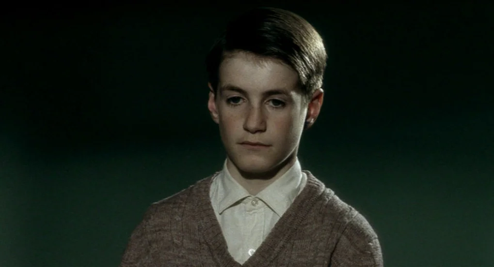The Long Day Closes (1992) movie still: closeup — A portrait against a dark, featureless backdrop with no visible environmental markers. A young boy…