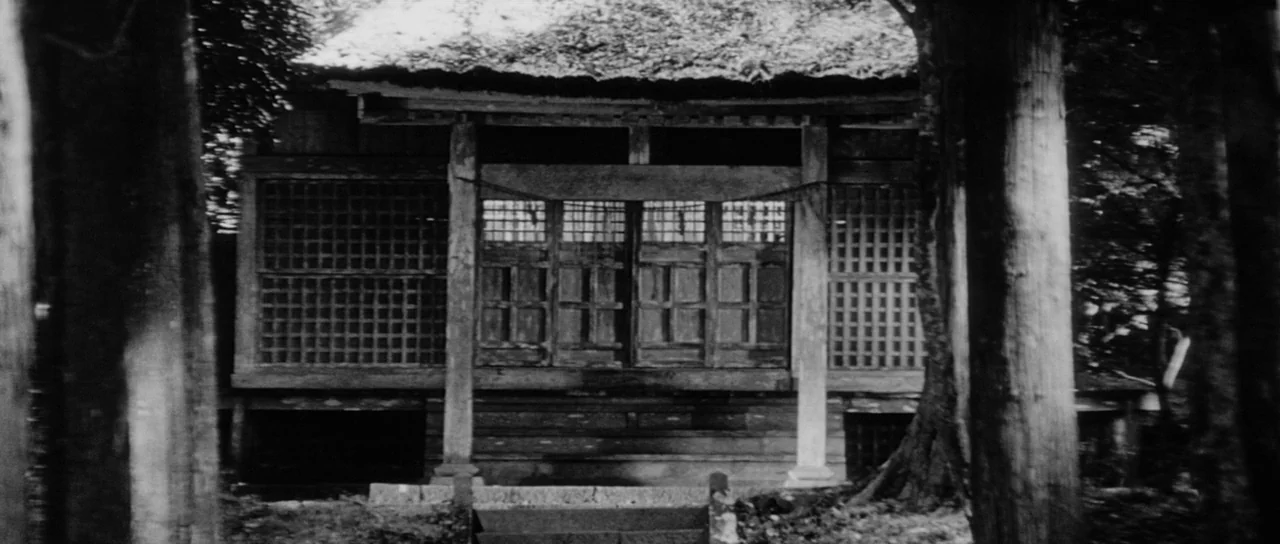 Sanjuro (1962) movie still: establishing — A traditional wooden Japanese structure with latticed windows sits nestled between tall dark trees. The…