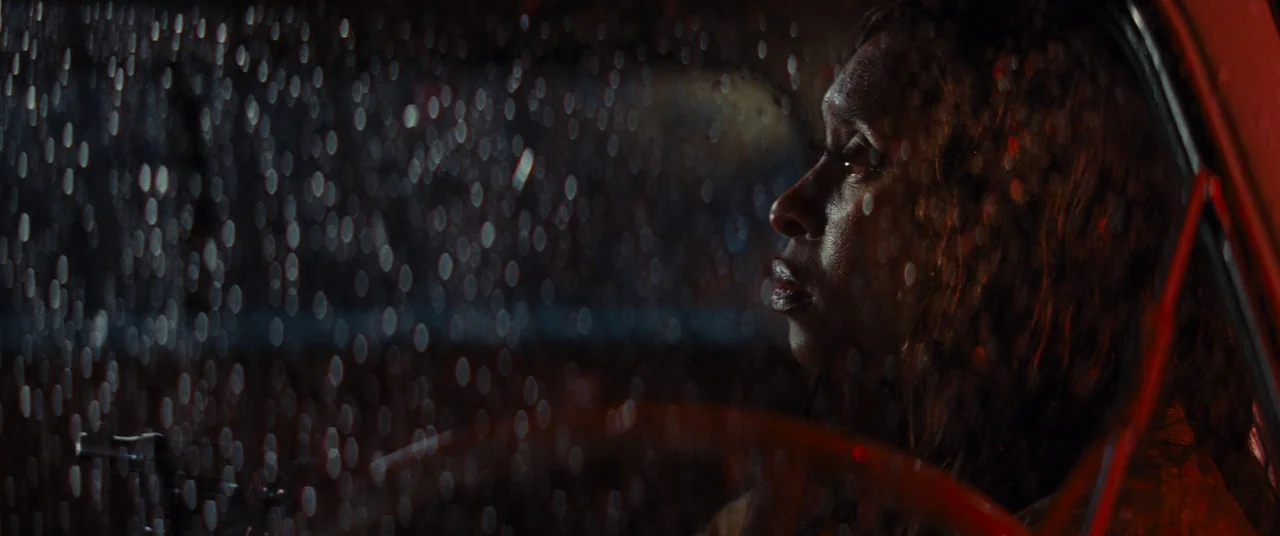 Bad Times at the El Royale (2018) movie still: closeup — The interior of a vehicle at night during a heavy rainstorm. A woman sits behind the…