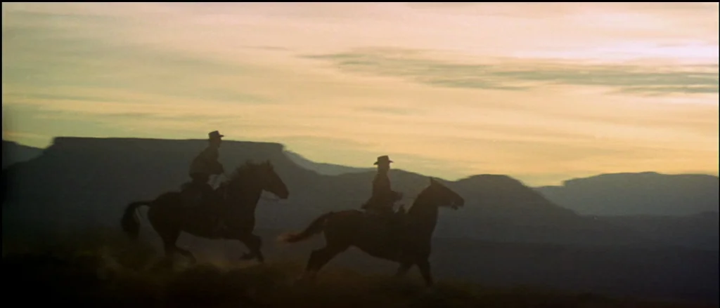 Butch Cassidy and the Sundance Kid (1969) movie still: wide — A vast, arid desert landscape features distant mesas silhouetted against a golden…