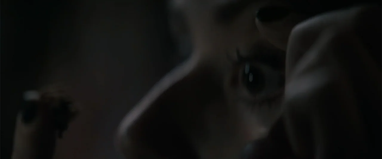 Equation of Love and Tone Deafness (2015) movie still: closeup — A dark indoor setting focuses on a human face in extreme low-key lighting. A hand…