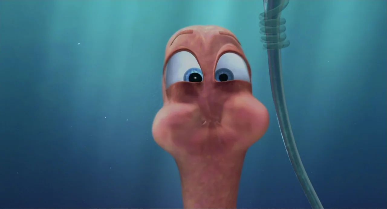 Shark Tale (2004) movie still: closeup — An underwater scene features a pink worm character with its mouth extended wide. The character floats…