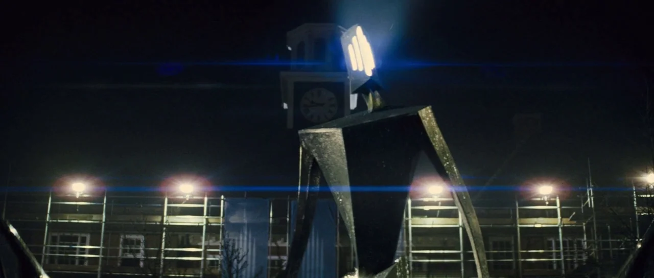 The World’s End (2013) movie still: wide — A dark night scene features a large, angular metallic sculpture standing in front of scaffolding. A…