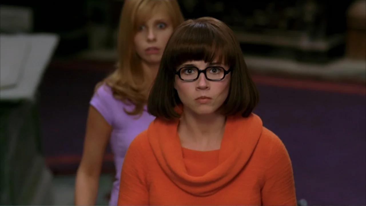 Scooby-Doo 2: Monsters Unleashed (2004) movie still: medium — An interior space with a dimly visible purple carpeted floor. Two women stand in the…