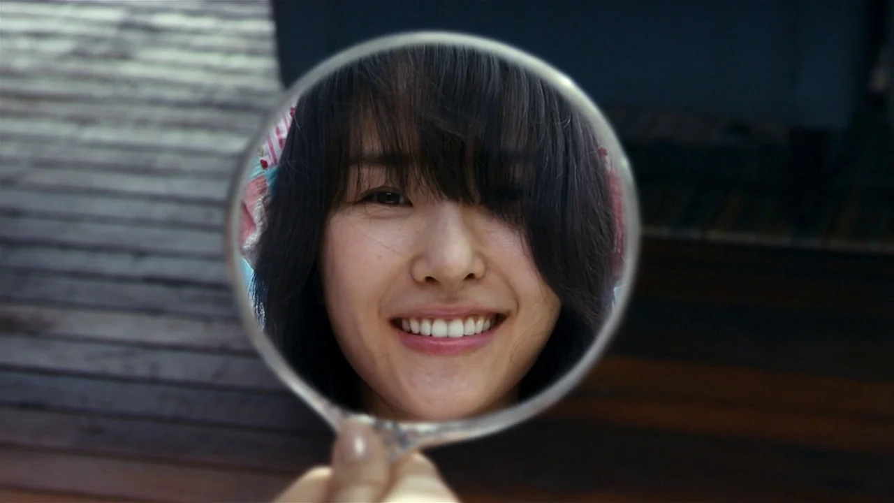 I’m A Cyborg, But That’s Okay (2006) movie still: closeup — A wooden interior room with a dark floor provides the setting for the shot. A woman…