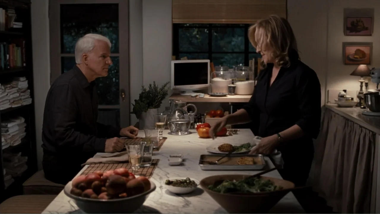 It's Complicated (2009) movie still: medium — A well-lit home space features a marble-topped center island with food and tableware. A mature man…