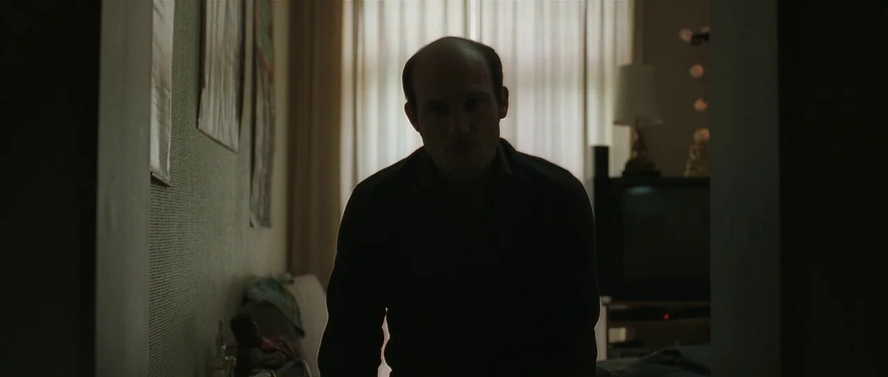 Bullhead (2011) movie still: medium — An interior space is dominated by a man standing in front of a window. The subject is backlit with textured…