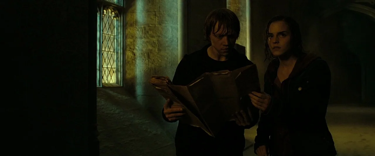 Harry Potter & The Deathly Hallows Part 2 (2011) movie still: medium — A dark stone passageway with a tall arched window glowing with moonlight. A…