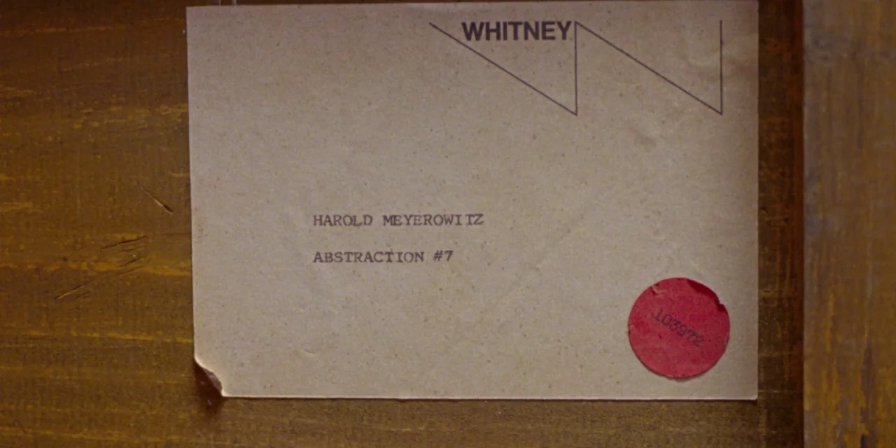 The Meyerowitz Stories (New and Selected) (2017) movie still: closeup — A tan paper label is attached to a textured wooden surface. The label…