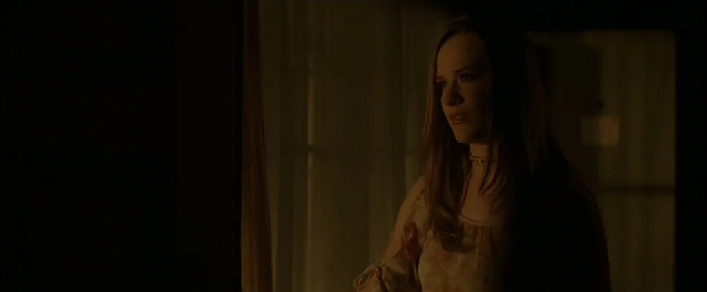 Down In The Valley (2005) movie still: medium — An interior bedroom features dark walls and sheer curtains partially obscuring a light source. A…