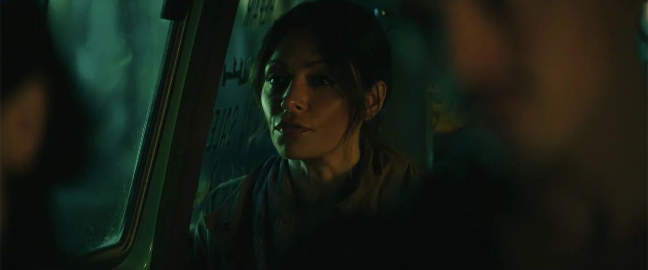 Black Adam (2022) movie still: medium — A dark vehicle interior with a window visible on the left side. A woman looks through the window while…
