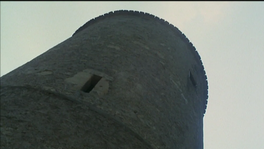 The Enigma Of Kaspar Hauser (1974) movie still: establishing — A tall circular stone tower rises against a clear overcast sky. The weathered stone…
