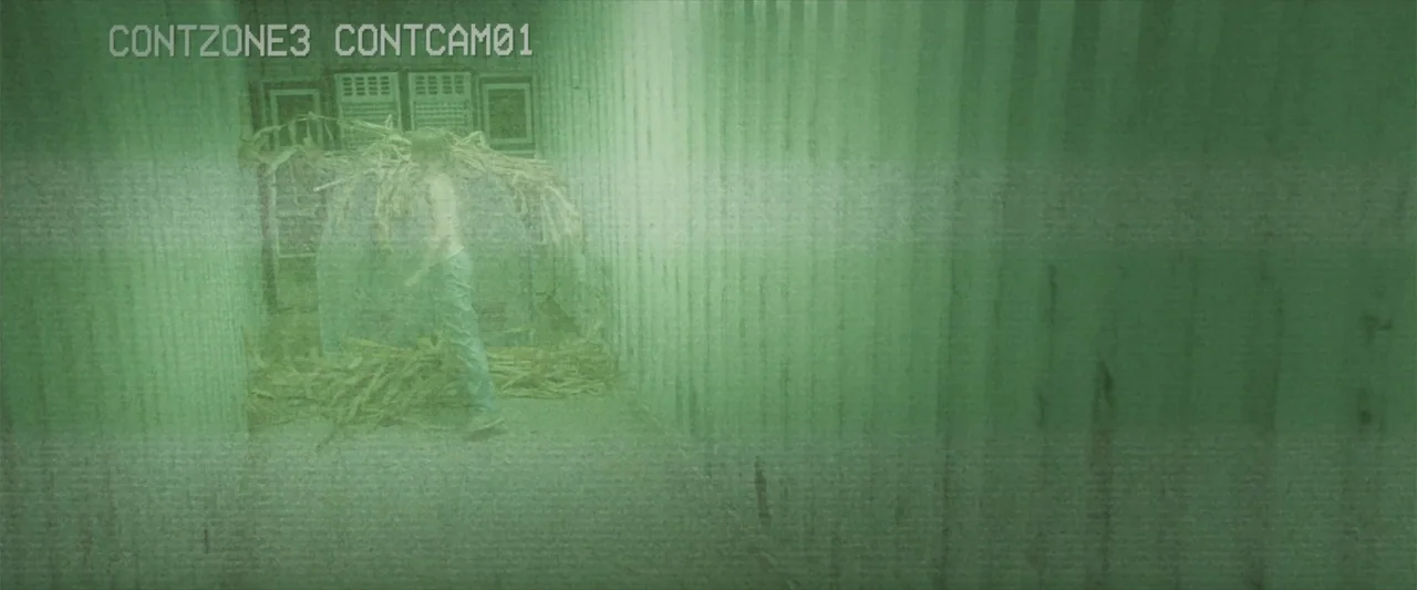 Treblinka's Last Witness (2012) movie still: fullbody — A narrow industrial corridor with ribbed metal walls contains a pile of dried vegetation. A…