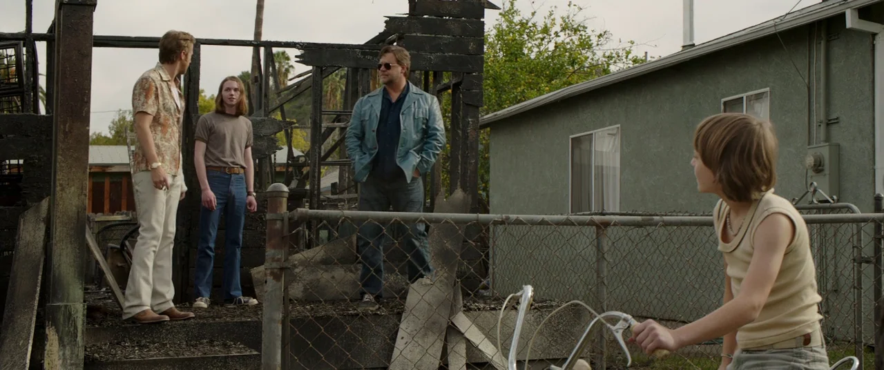 The Nice Guys (2016) movie still: wide — A suburban residential lot containing the burnt remains of a wooden house. Three men stand near the charred…