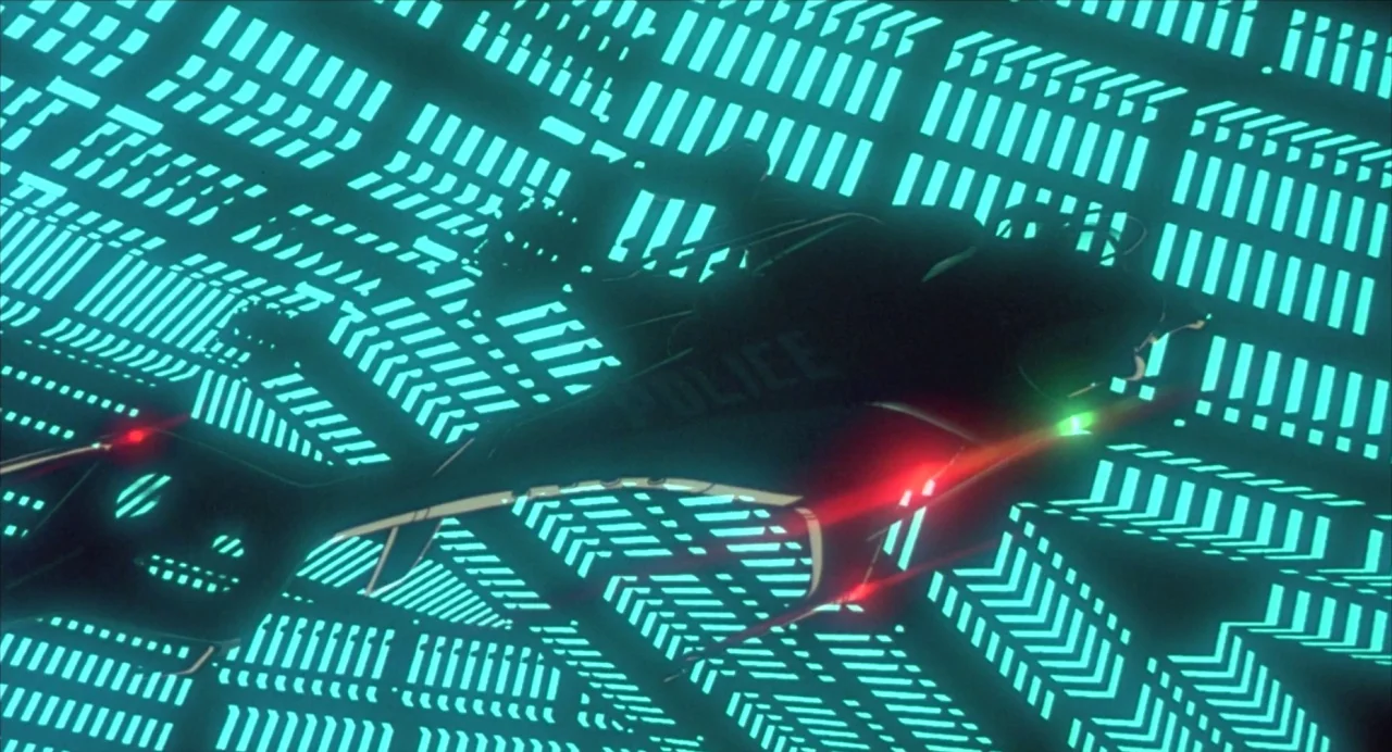 Ghost in the Shell (1995) movie still: wide — A dark flying police vehicle traverses a vast surface covered in rhythmic, glowing cyan patterns. The…