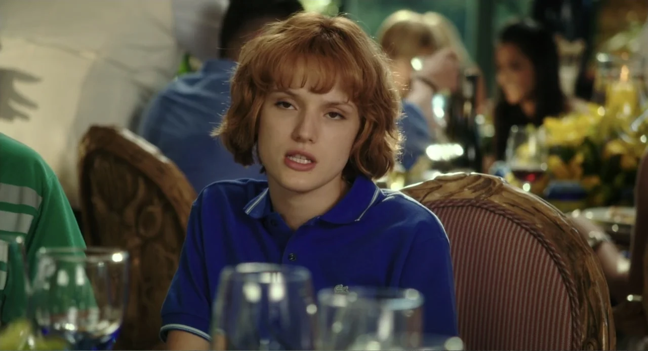 Blended (2014) movie still: medium — A person sits at a dining table inside a restaurant with blurred background diners. The woman with reddish hair…