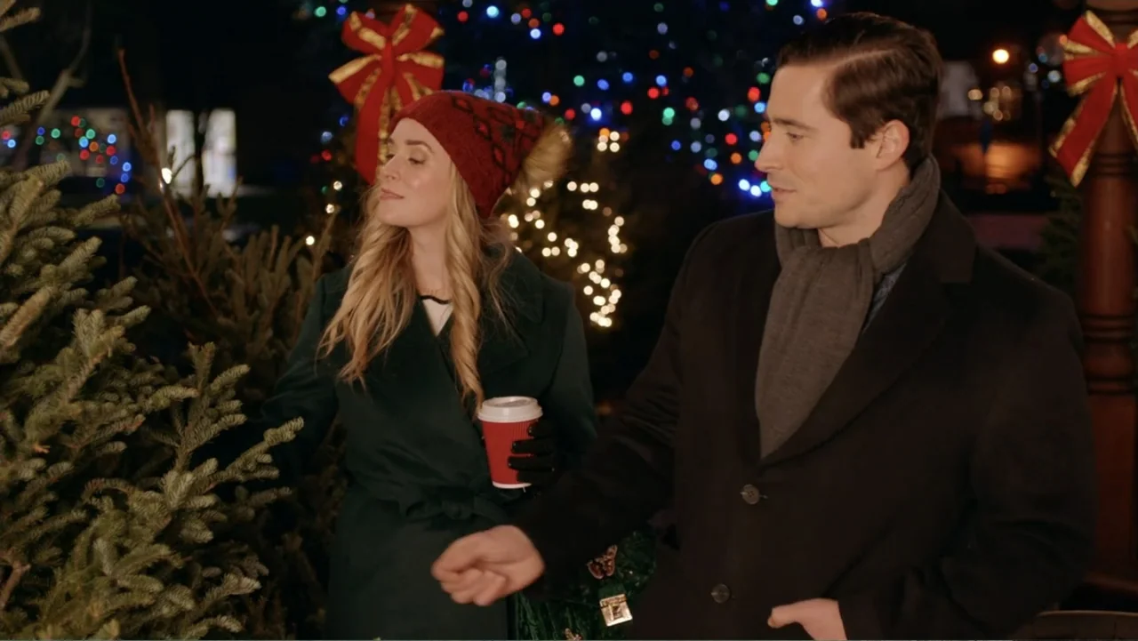 Loving Christmas (2022) movie still: medium — Outdoor evening setting at a tree lot with blurred colorful holiday lights in background. A man and…