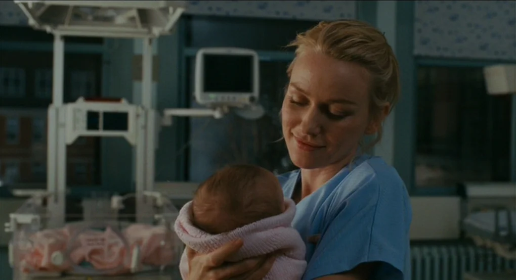 Eastern Promises (2007) movie still: medium — A hospital room features medical monitors and a bassinet in the blurred background. A woman in blue…