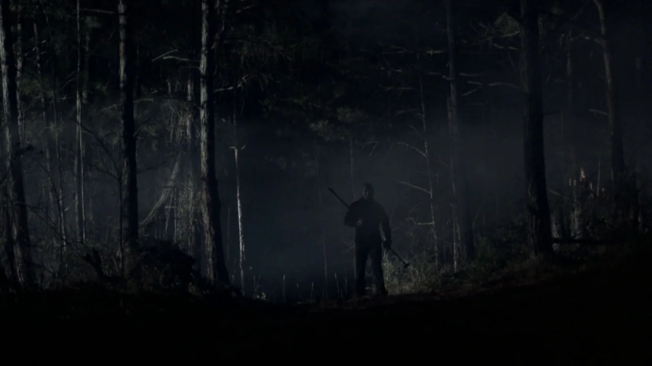 Friday the 13th Part VI: Jason Lives (1986) movie still: wide — A dark, dense forest filled with tall pine trees and low-hanging fog at night. A…