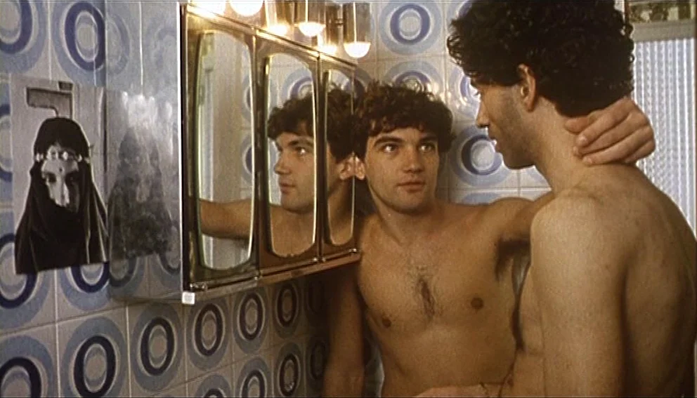 Labyrinth of Passion (1982) movie still: medium — A bathroom wall features blue and white circular patterned tiles and a medicine cabinet. Two…