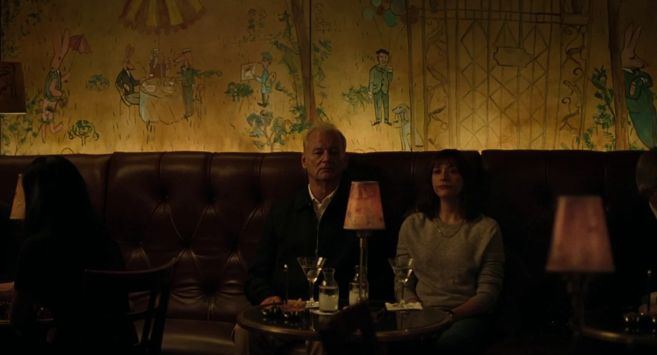On The Rocks (2020) movie still: medium — An intimate lounge features a button-tufted leather banquette against a wall with hand-painted murals. A…