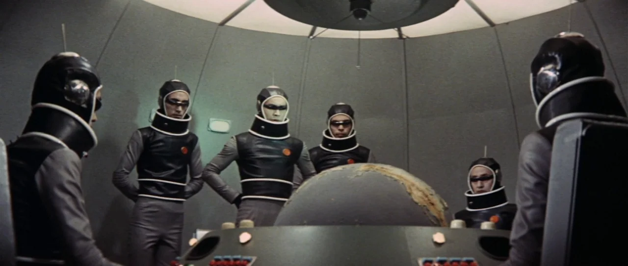 Invasion of Astro Monster (1965) movie still: wide — A circular room features curved walls and a central console containing a large globe. Five…
