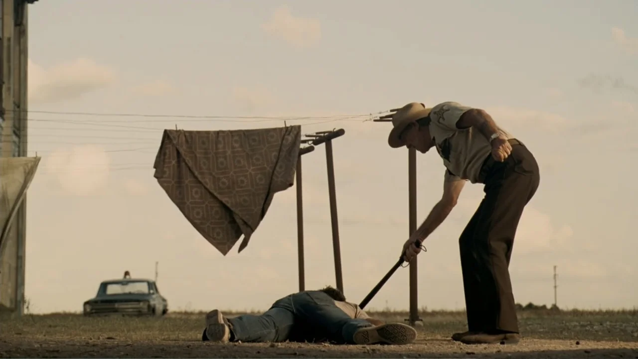 The Texas Chainsaw Massacre: The Beginning (2006) movie still: fullbody — An open gravel lot during the golden hour with a clothesline and vehicle…