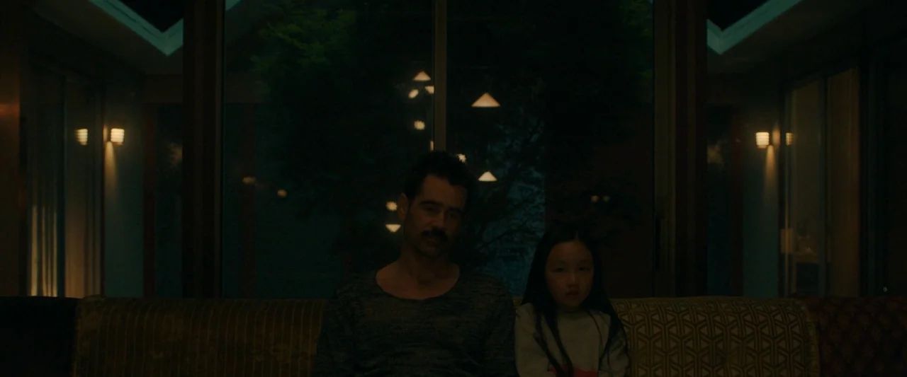 After Yang (2021) movie still: medium — A dark, modern living room at night featuring large glass sliding doors and sconces. A man and a young girl…
