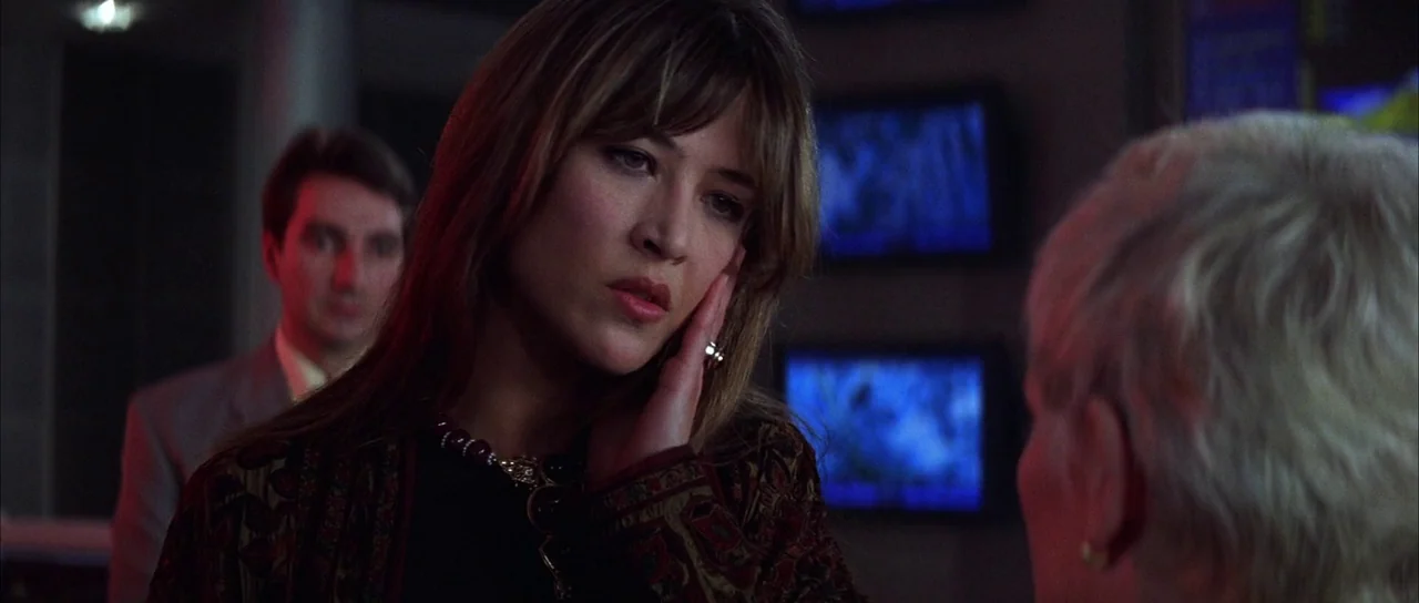 The World is Not Enough (1999) movie still: medium — A dimly lit room contains multiple computer monitors displaying glowing blue graphics on the…