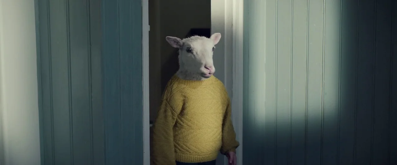 Babel (2006) movie still: medium — A person with a sheep mask stands in a doorway between two teal walls. The subject is positioned centrally in the…
