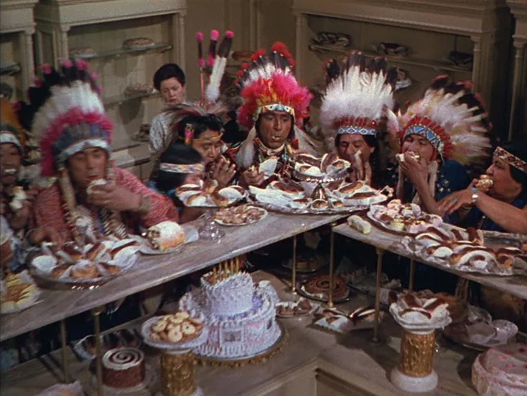 Annie Get Your Gun (1950) movie still: medium — A well-lit commercial interior with glass display cases filled with various baked desserts. Several…