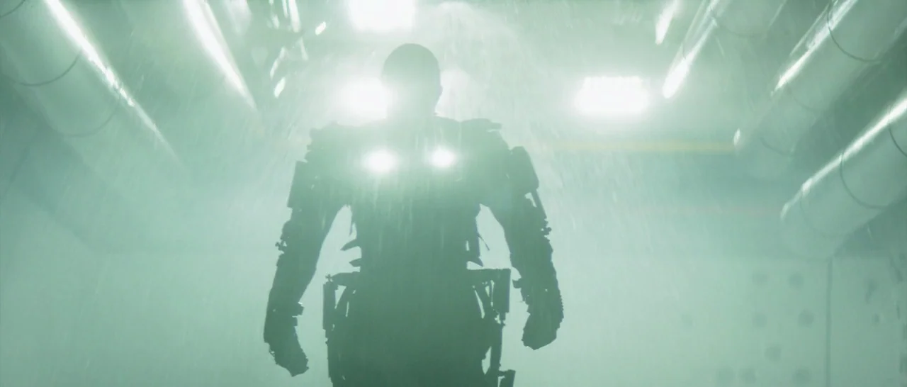 Elysium (2013) movie still: fullbody — A high-ceilinged industrial facility is filled with airborne water mist and steam. An armored robotic figure…