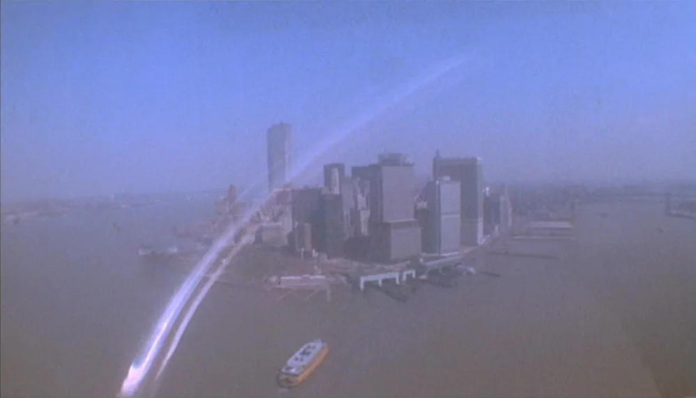 Marathon Man (1976) movie still: establishing — A hazy aerial view of the lower Manhattan skyline surrounded by the Hudson River. A single bright…