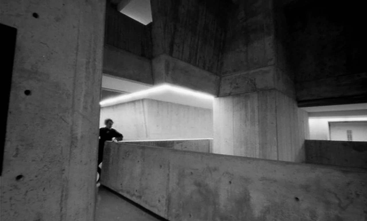 Stereo (1969) movie still: wide — A monolithic concrete interior features sharp angles and layered levels of brutalist architecture. A solitary…