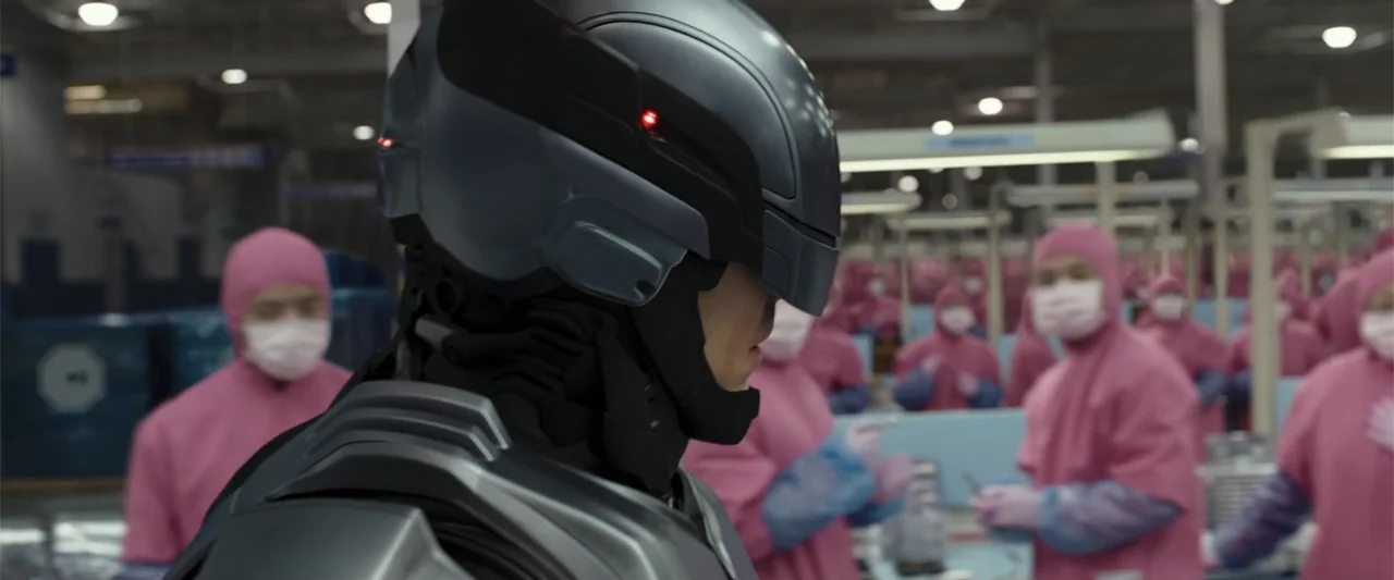 RoboCop (1987) movie still: medium — A vast, sterile assembly plant features rows of workers dressed in matching pink uniforms. In the foreground, a…