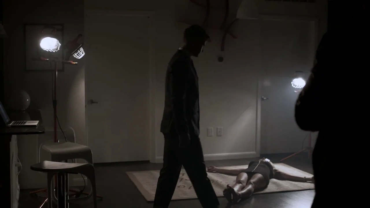 Hellraiser: Judgement (2018) movie still: fullbody — A sparsely furnished room with dark floors and white walls is illuminated by work lights. A man…