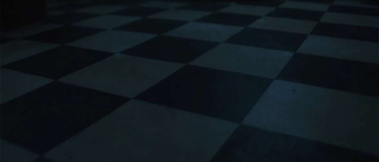 All Fun and Games (2023) movie still: establishing — A close perspective of a dark checkered floor with alternating black and white tiles. No…