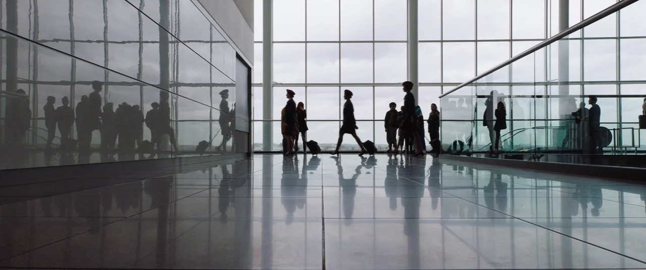 Fighting With My Family (2019) movie still: wide — A modern airport terminal features polished tile floors and floor-to-ceiling glass panel walls.…