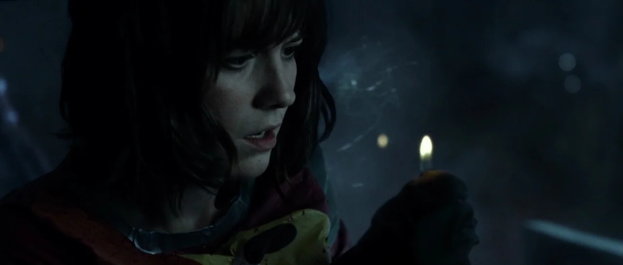 10 Cloverfield Lane (2016) movie still: closeup — A dark, enclosed space with shadowy backgrounds that obscure architectural detail. A young woman…