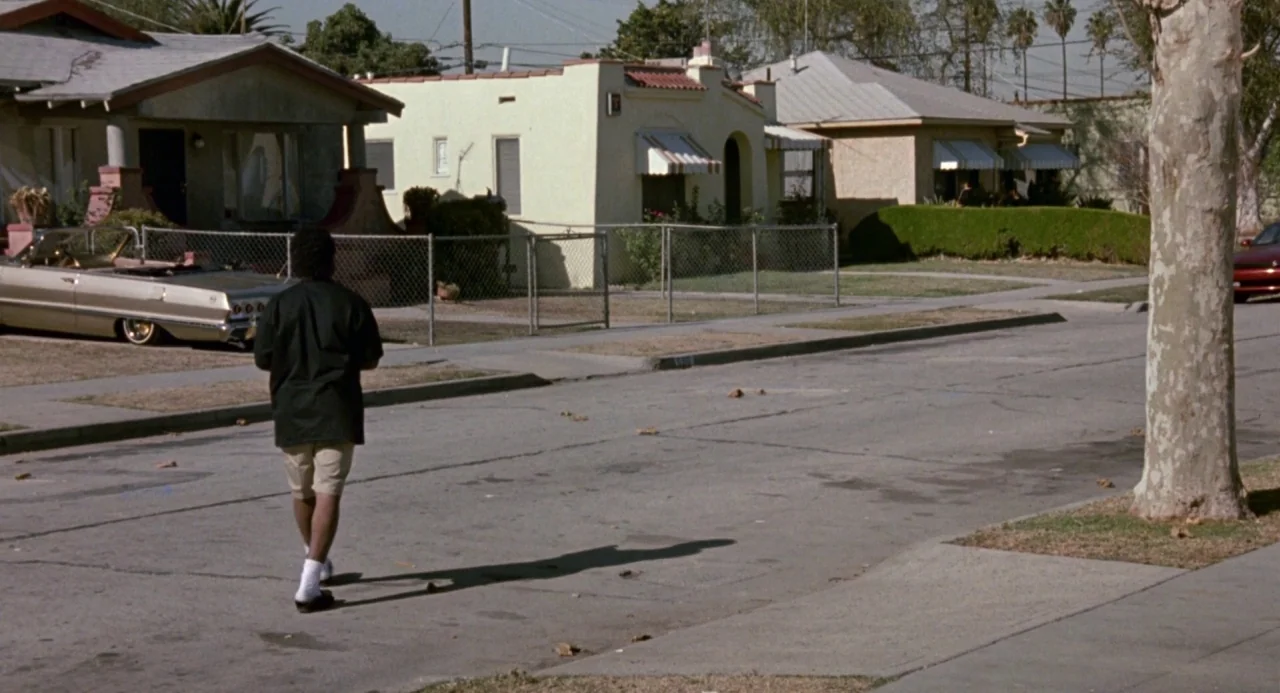 Boyz In The Hood (1991) movie still: fullbody — A residential neighborhood in Los Angeles with single-story stucco houses and chain-link fences. A…