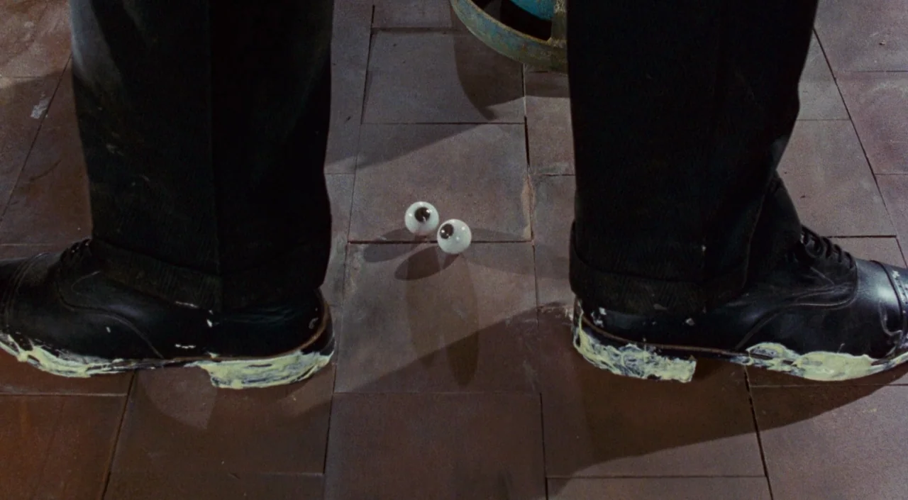 Who Framed Roger Rabbit (1988) movie still: closeup — A pair of black leather dress shoes stand on brown square tiles. Two detached prosthetic…