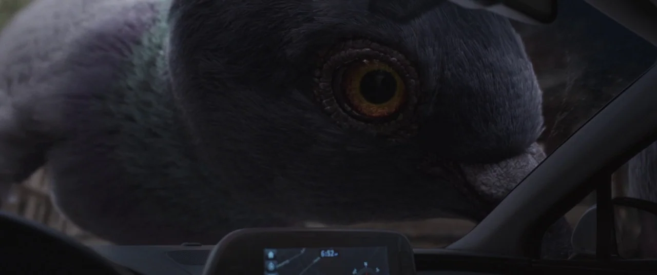 Ant-Man and the Wasp (2018) movie still: closeup — A massive bird face looms directly outside the windshield of a modern vehicle interior. The large…